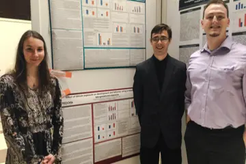 psychology students pose in front of the research presentation posters