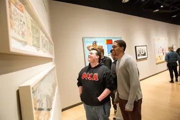 students look at art pieces during a gallery opening