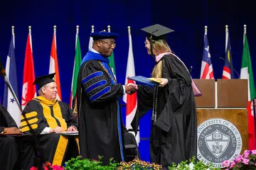 President Stephen H. Kolison Jr. congratulates a student crossing the stage.
