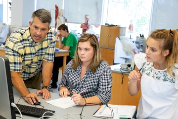 a biology professor offers feedback to two students in a computer