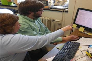a fredonia professor points to a computer while advising a student