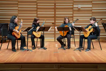 Fredonia students playing guitars during a performance at the school of music. 