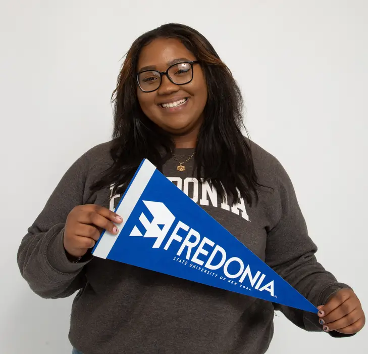 Harmony Buchanan smiling and holding a Fredonia pennant 