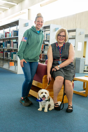 therapy dog with trainer and library director