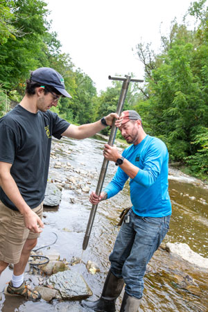 Randy Blood (right) removes a segment of core from the hollow drill bit with assistance from Hayden Backus.