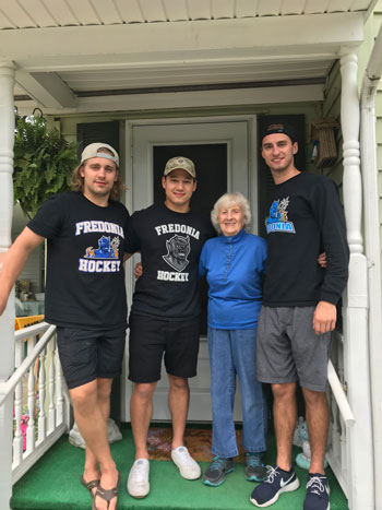 Tanner Kahlau with teammates and community member on porch