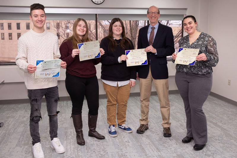 George Simmons posing with 3 students & 1 recent graduate holding their B2B Scholarship Certificates