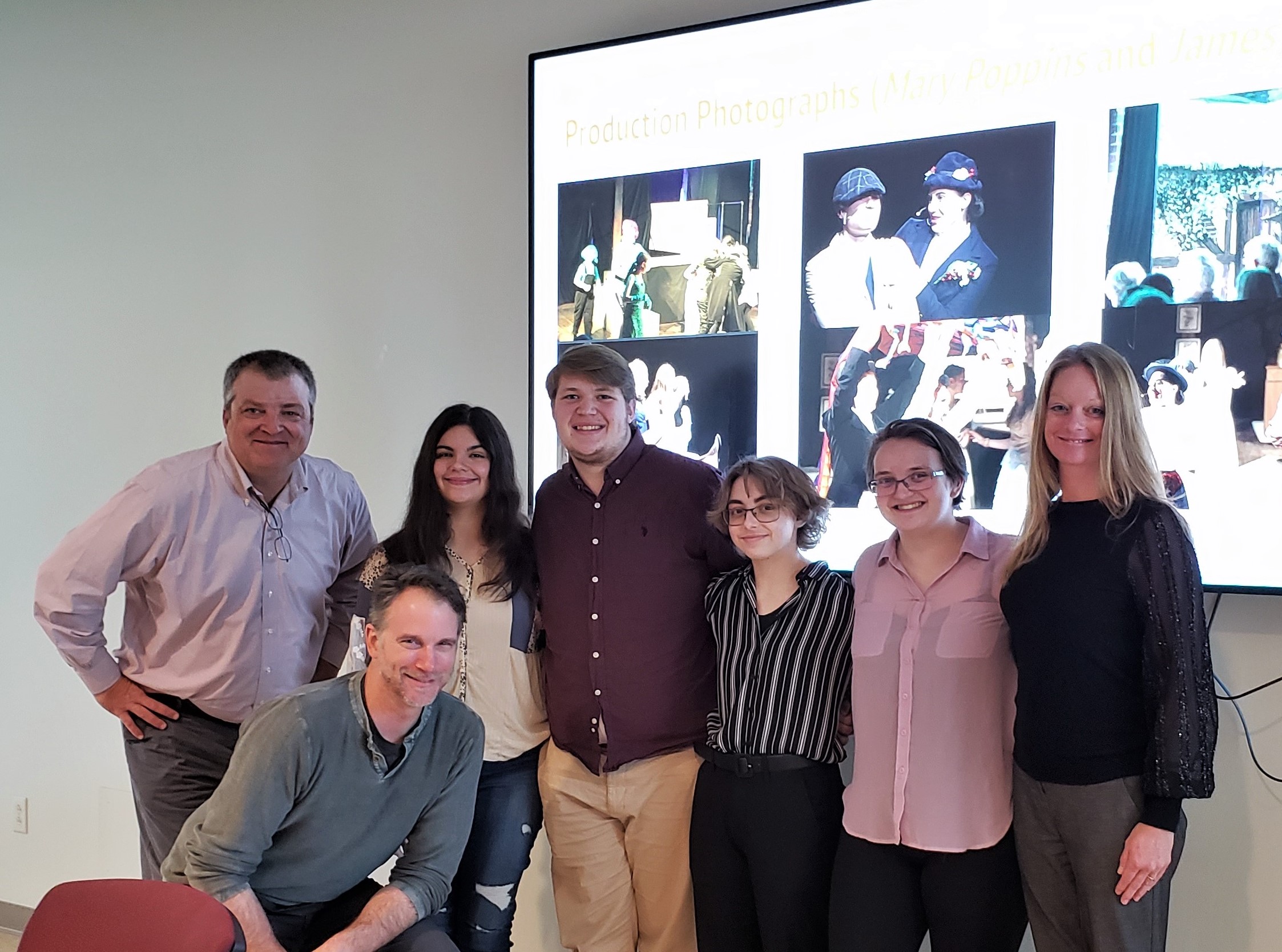 Summer 2022 Fellows posing with Ted Sharon, Chuck Cornell, and Lauri Gawronski in from of a slide from their final presentation