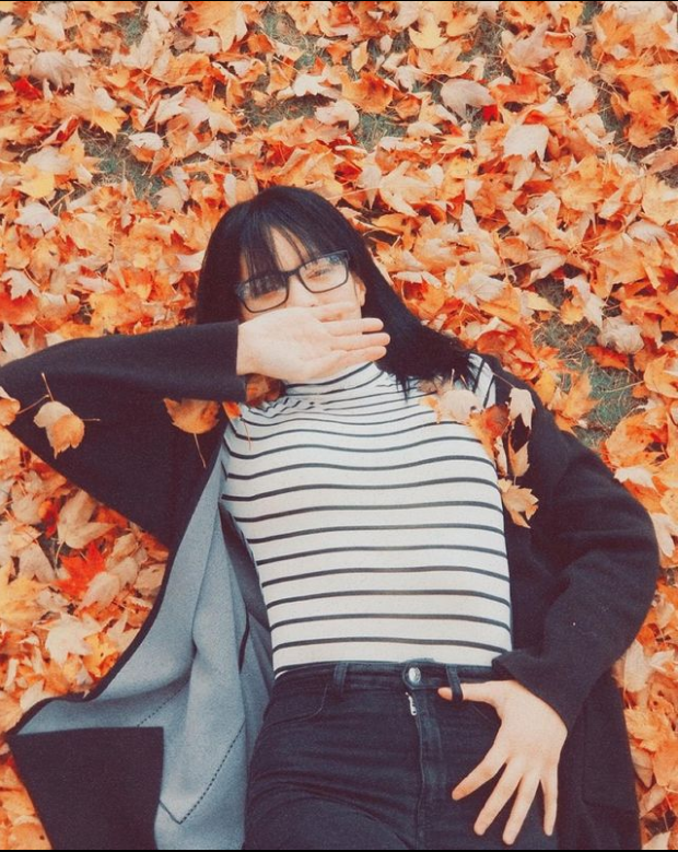 Picture of intern Rosa Vargas laying in a pile of fallen leaves