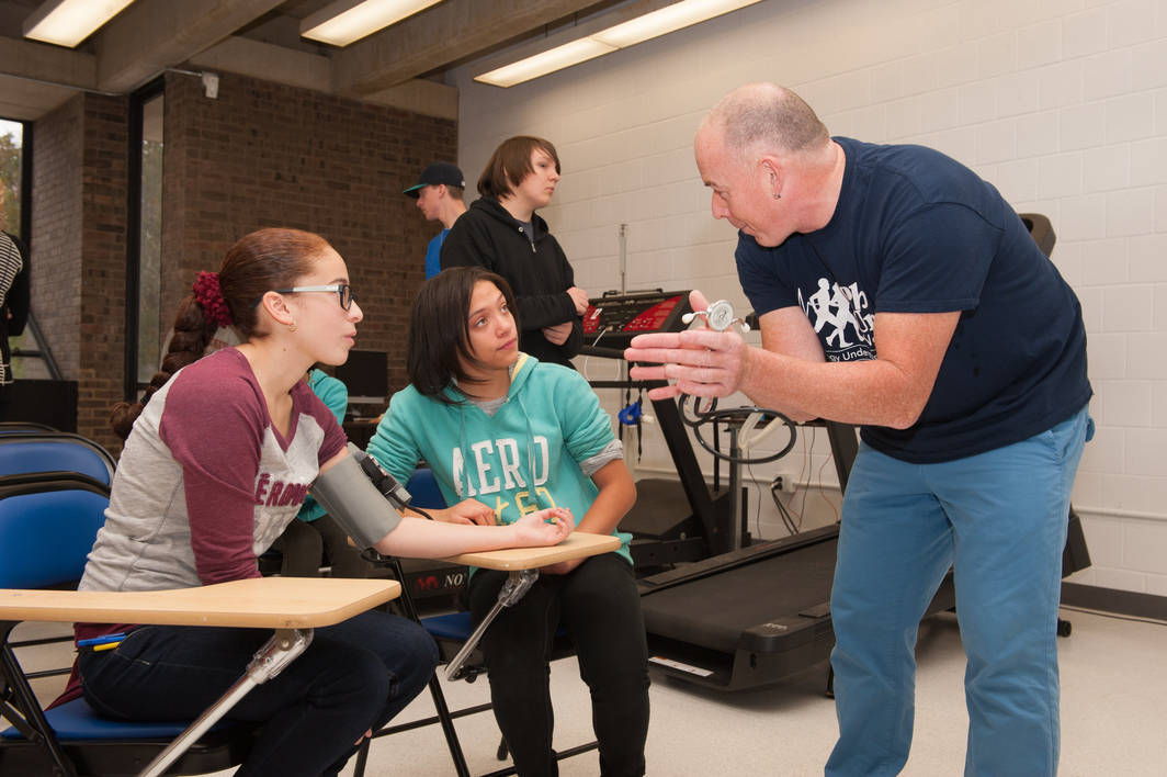 An instructor speaks to two Fredonia exercise science students