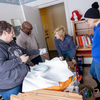 President Stephen H. Kolison Jr., Vice Provost Judy Horowitz, Associate Director of Human Resources Jennifer Costa and Dr. Naomi Baldwin sort through merchandise at Chautauqua County Rural Ministry.