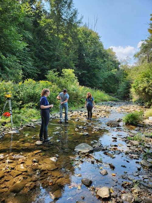 SUNY Fredonia Geology majors (from left) Elizabeth Wightman, Brett Boyer and Abigail Nordwall collect suspended sediment water samples in Dewittville Creek, Geology major