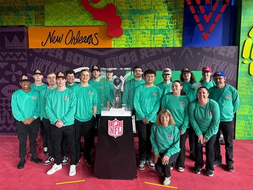 a group of students and faculty in front of the Lombardi Trophy