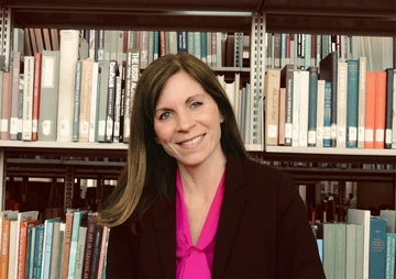 Dr. Emily VanDette in front of shelves of books
