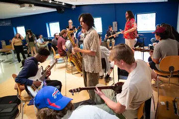 Fredonia students playing saxophone and guitars at a campus event.