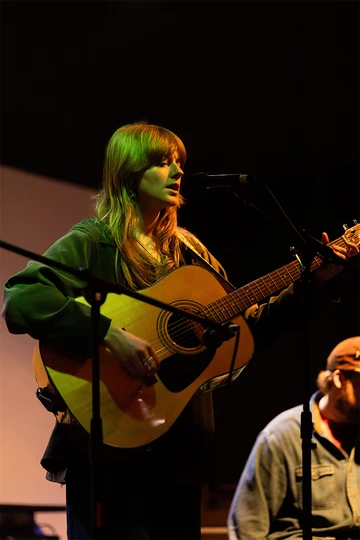 singer standing, playing guitar and singing