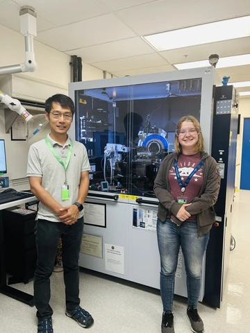Dr. Wentao Cao and Mia Enders, alongside an XRD (x-ray diffraction) machine at the Pacific Northwest National Lab.