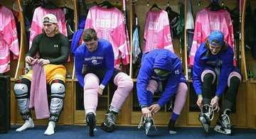 hockey players with pink jerseys hanging in background, men's ice hockey