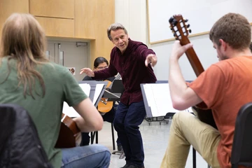 SUNY Distinguished Professor James Piorkowski interacts with students in a guitar class