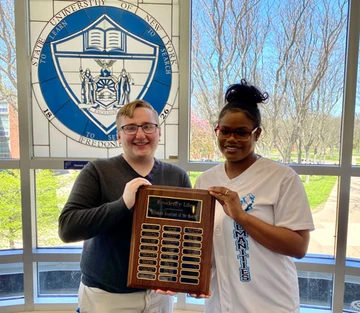 photo of two students with plaque