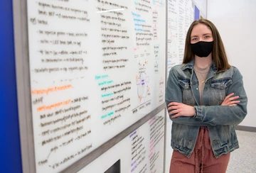 student in front of whiteboard with research information