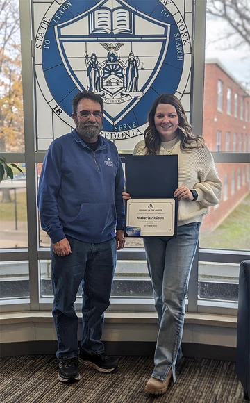 Makayla Neilson standing with her certificate with Mark Mackey