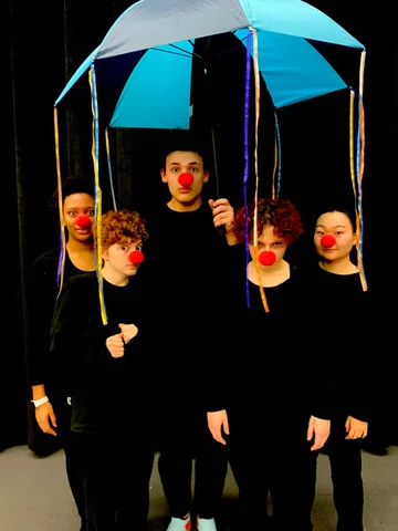 student mimes standing under and umbrella, Theatre major