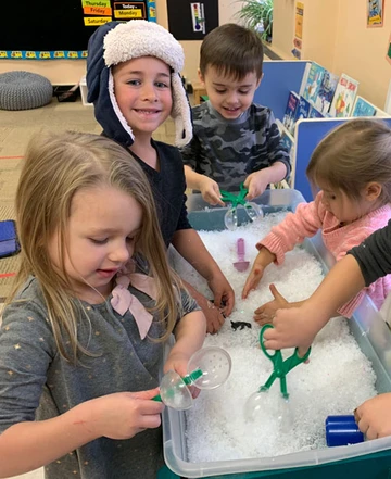 Children having fun exploring their five senses and playing at the sensory table.