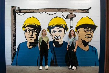 students post in front of the mural they painted