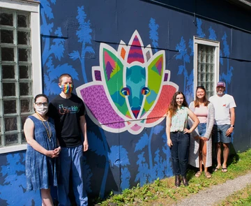 students and faculty in front of mural