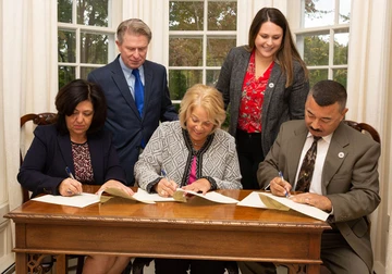 President Virginia Horvath, flanked by Fredonia Mayor Athanasia Landis, Dunkirk Mayor Willie Rosas, sign documents that formaliz