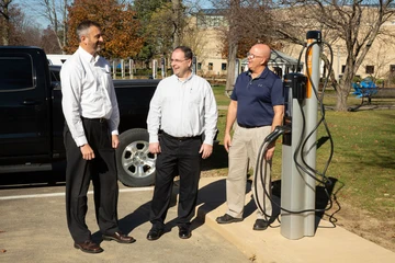 Staff members next to EV charging station