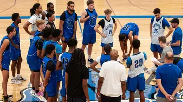 basketball players surrounding coach on court