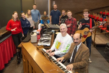 students and faculty around donated piano