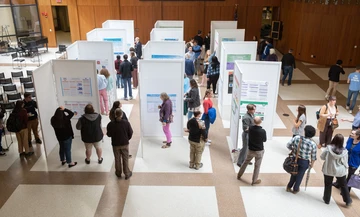 Visitors navigate around student poster presentations in the Williams Center Multipurpose Room during the OSCAR expo.