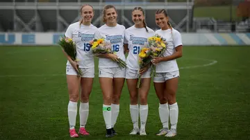 four senior soccer players with flowers