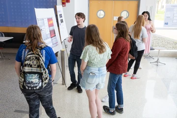 student presenting a poster to other students