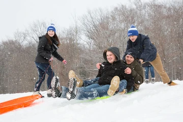 students sledding in the snow