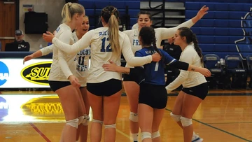 Fredonia State volleyball players celebrating on court, volleyball