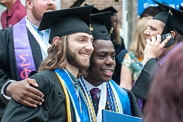 graduates pose for photo with their diploma