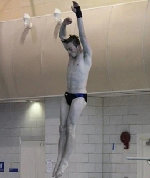 a diver is in mid-air as he jump on the board to begin his dive