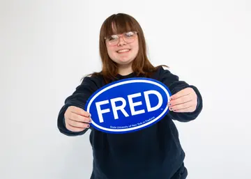 Morgan Brown smiling and holding a FRED sign