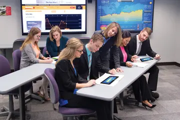 a business professor leans references a student's work on their desk during a business class