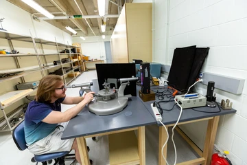 Student at a table doing research. Physics major uses advanced equipment, showcasing Fredonia's state-of-the-art facilities.