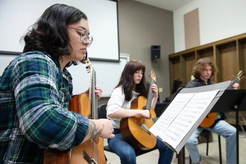 Fredonia music students playing guitars in a classroom