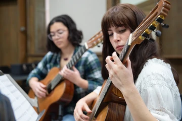 Fredonia students playing guitars, maintaining their performance edge.