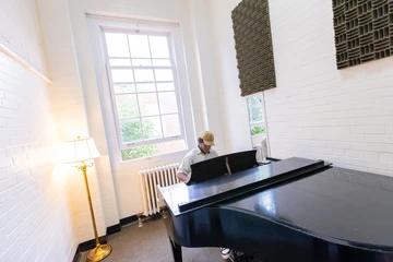 a student practices piano in a practice room