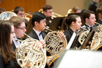 Fredonia wind ensemble student performing in a concert hall on campus