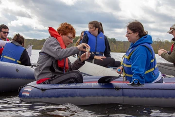 a biology student conducts research while in a canoe on a local waterway