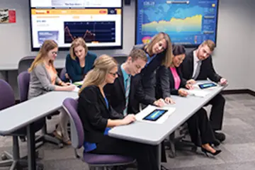 a business professor references a student's work on their desk during a business class